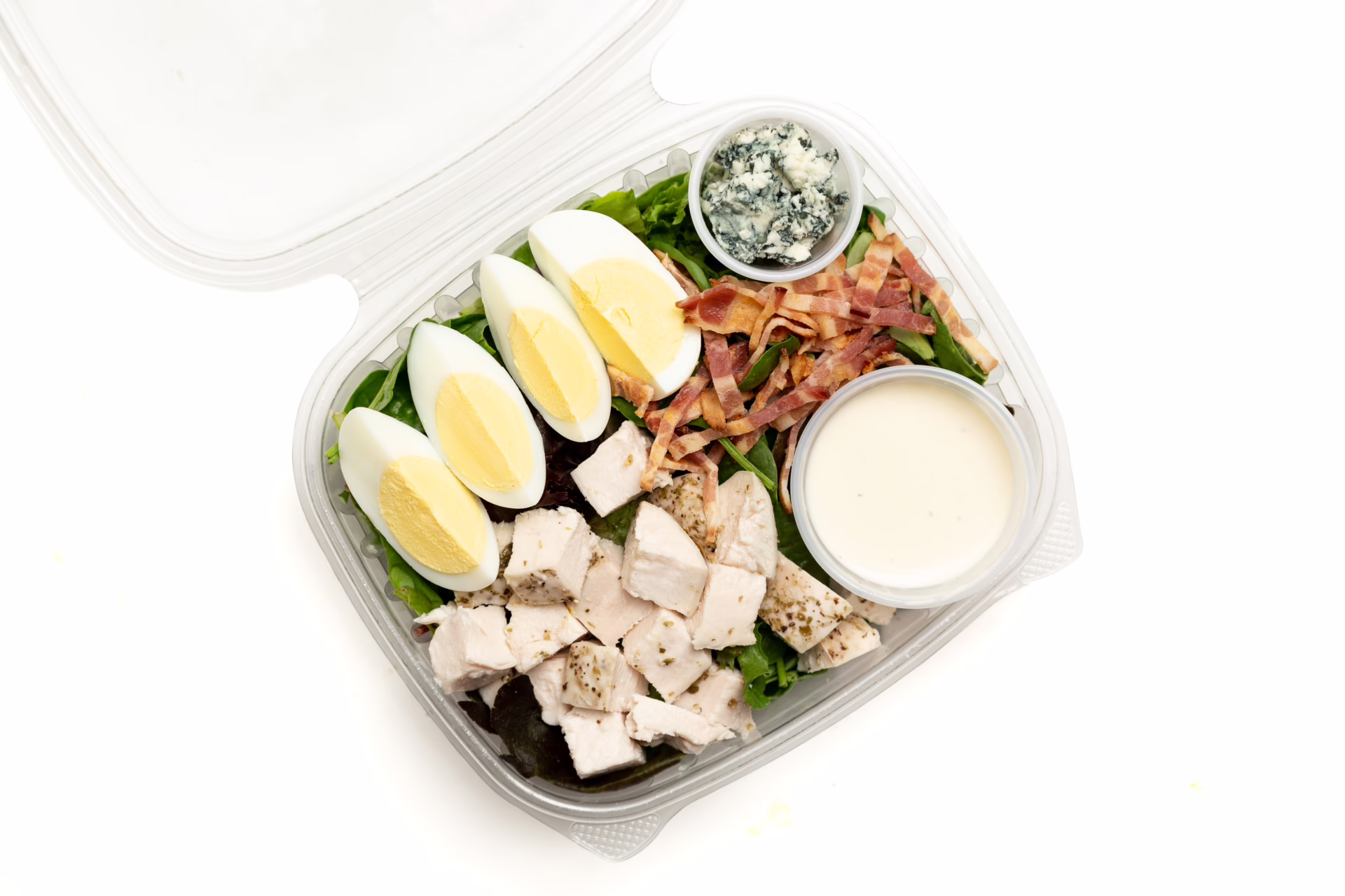 Mix baby greens, chicken breast, bacon, hard boil egg, blue cheese, lemon wedge, caesar dressing, parmesan cheese