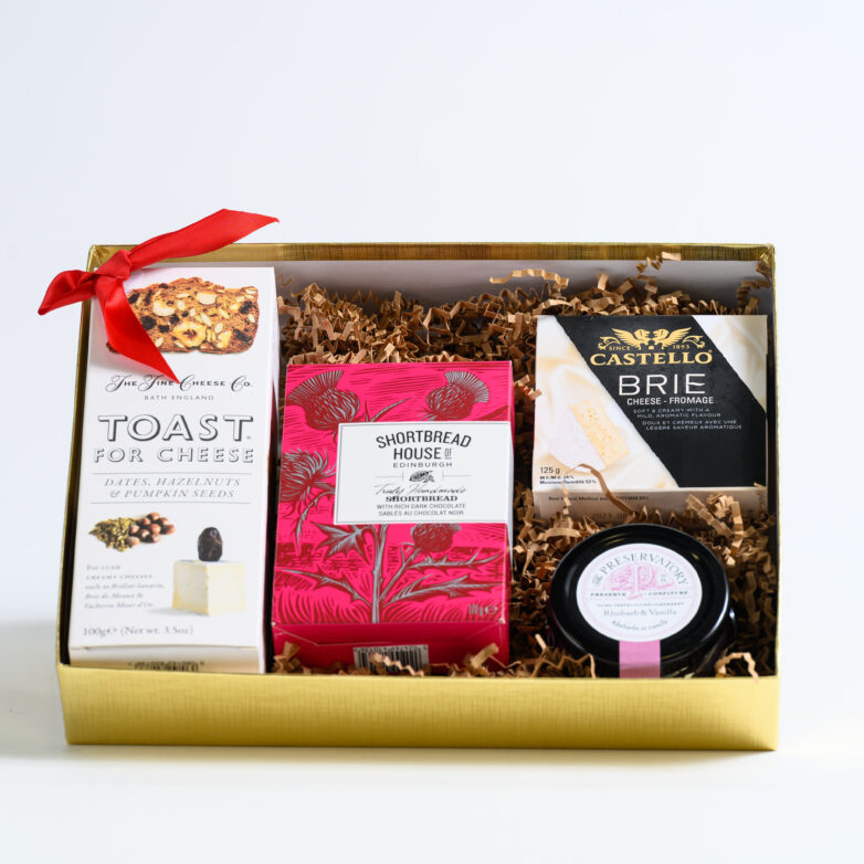 A gift box in golden rectangular packaging with savory and sweet snacks - with a ribbon on the top left corner.