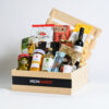 Gift Basket on a wooden crate with Food lovers Snacks inside, placed on a white background