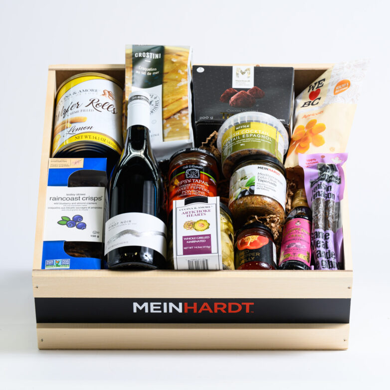 Snacks and Treats packed in a wooden crate with one wine in the front. The wooden crate is faded Beige color with a black strip and has Meinhardt written on it.
