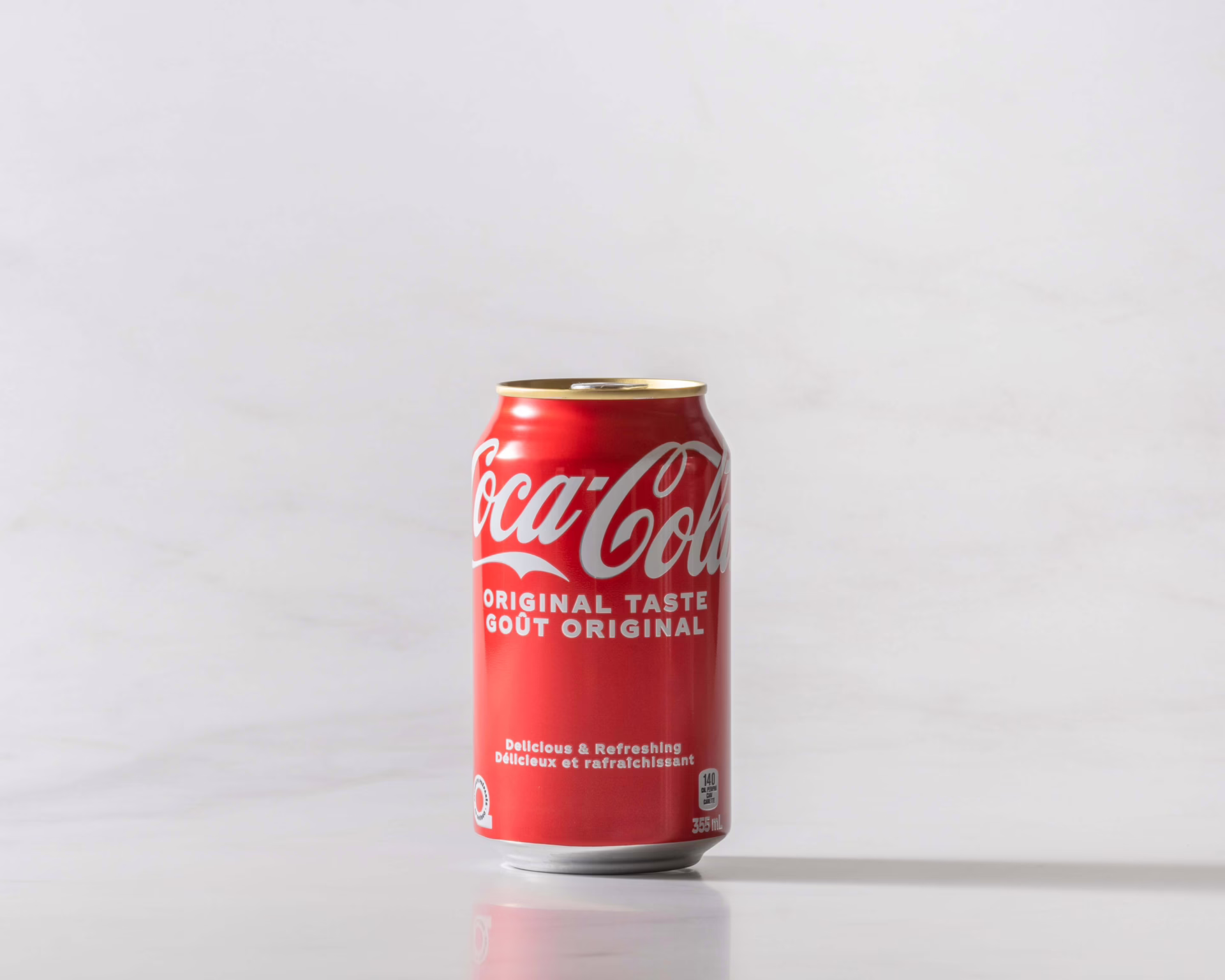 A can of Coke original on a table with a shadow to the right. Theme white marble.