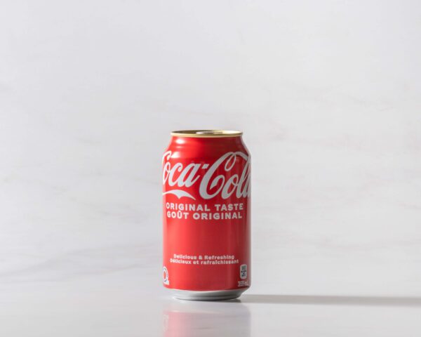A can of Coke original on a table with a shadow to the right. Theme white marble.