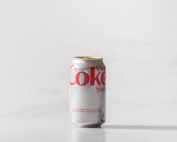 A can of Diet Coke original on a table with a shadow to the right. Theme white marble.