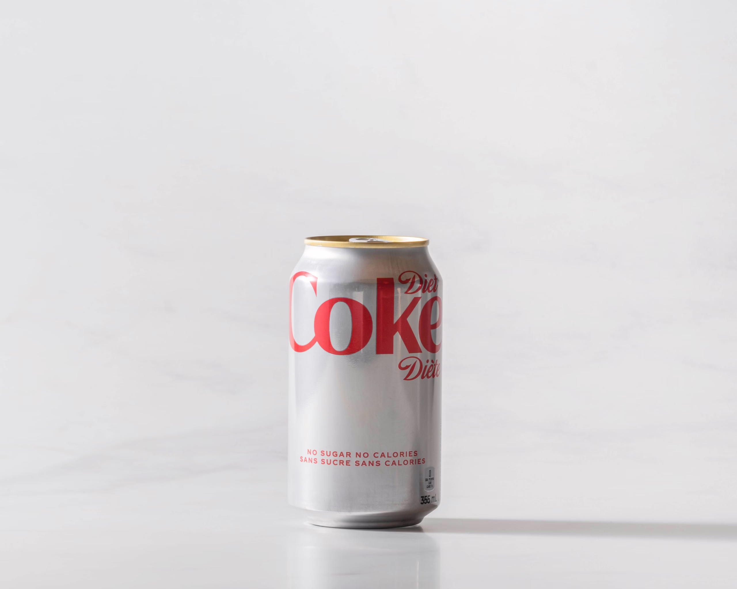 A can of Diet Coke original on a table with a shadow to the right. Theme white marble.