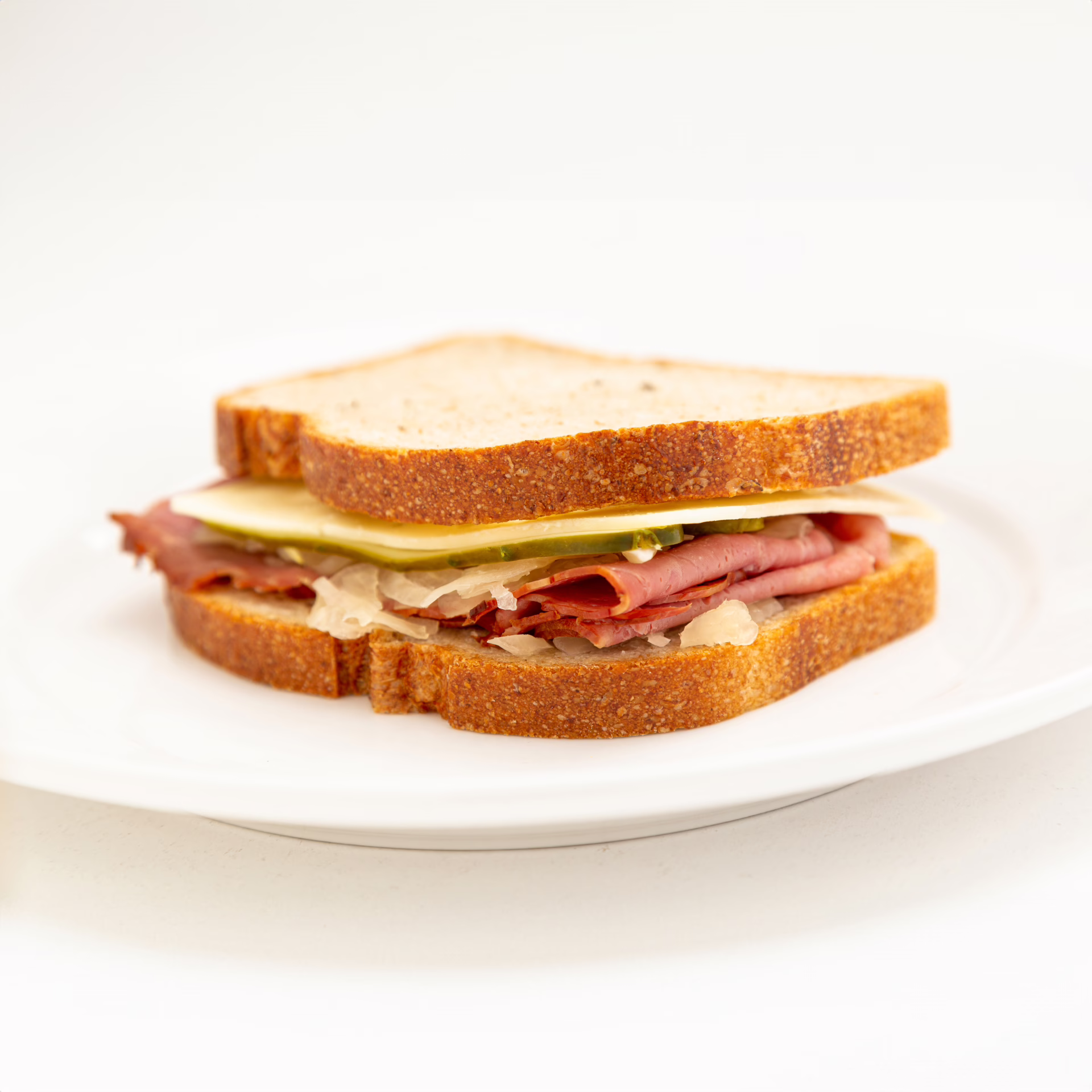 Whole Wheat Bread wrap with Chorizo, Cheese, Corned Beef, Mayo, tangy sauerkraut presented on a white plate