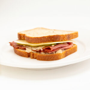 Whole Wheat Bread wrap with Chorizo, Cheese, Corned Beef, Mayo, tangy sauerkraut presented on a white plate