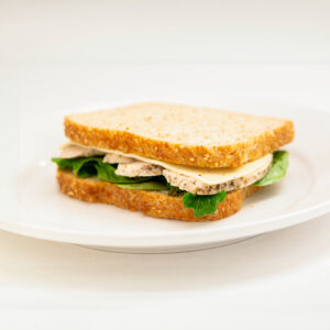 Whole Wheat Sesame Bread wrap with Grilled Chicken, Cheese, Spinach, Mayo presented on a white plate