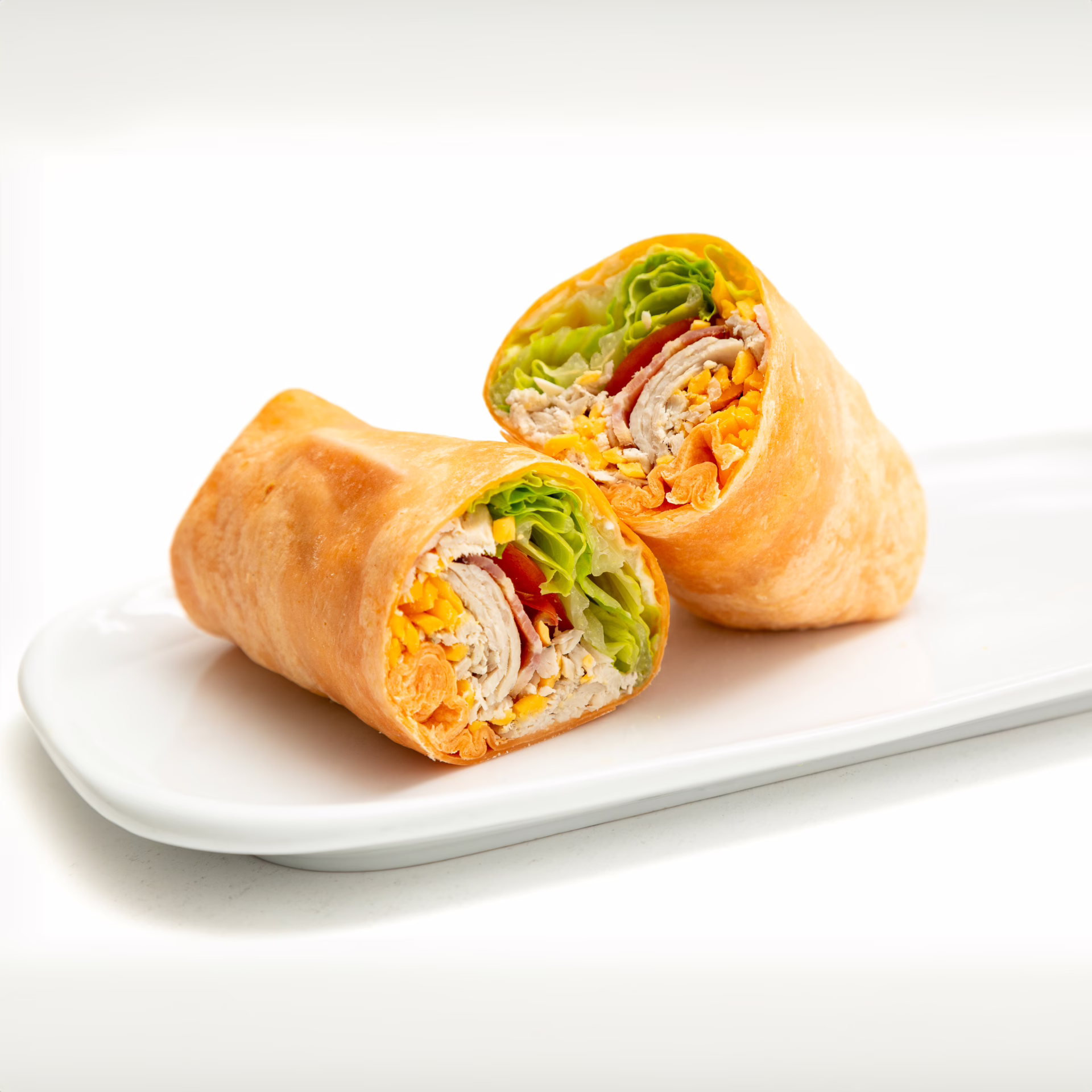 Cheddar flour tortilla wrap with Scrambled Eggs, Cheddar Cheese, Chicken inside presented on a white plate
