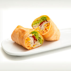 Cheddar flour tortilla wrap with Scrambled Eggs, Cheddar Cheese, Chicken inside presented on a white plate