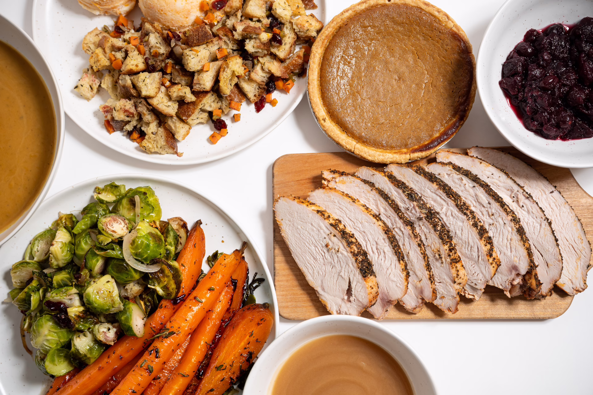 Meinhardt thanksgiving dinner with sliced turkey breast, stuffing, brussels sprouts, carrots, gravy, cranberry sauce and pumpkin pie.